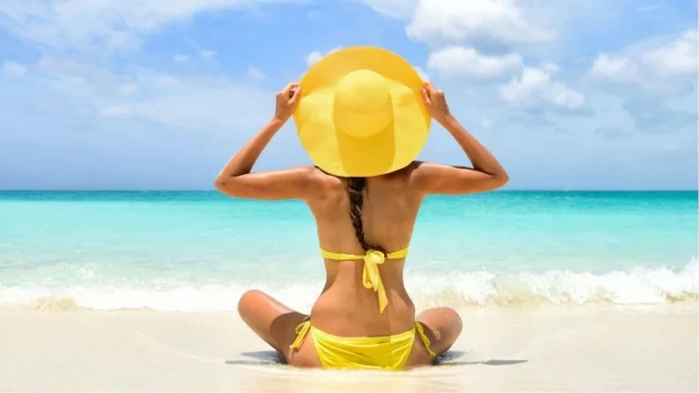 woman sat on beach looking at the waves